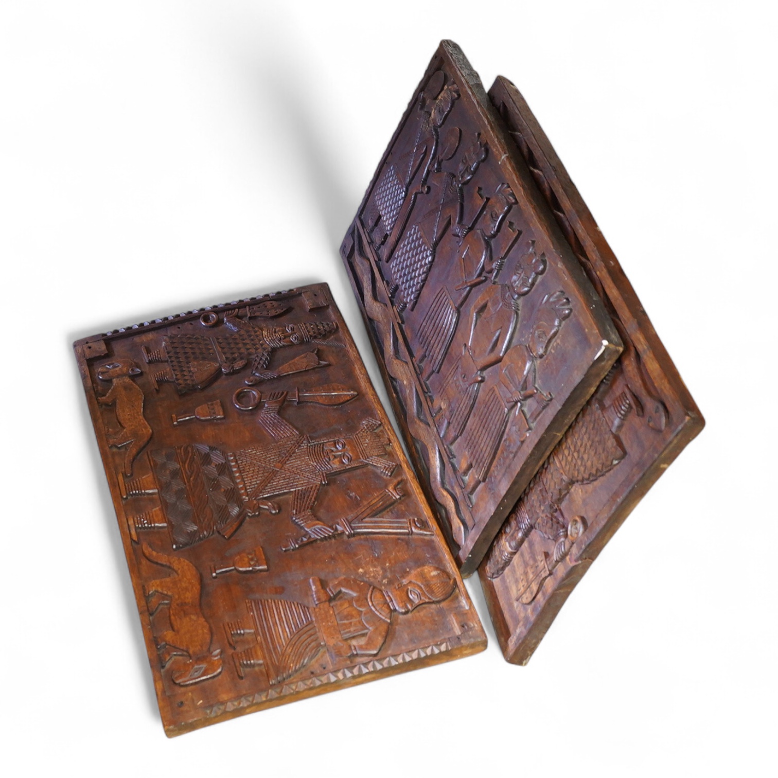 A set of three African carved figurative wooden panels, 64.5cm wide x 37cm high